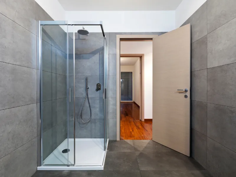 stanza-rivestita-con-mattonelle-grige-doccia-e-porta-in-legno-chiaro